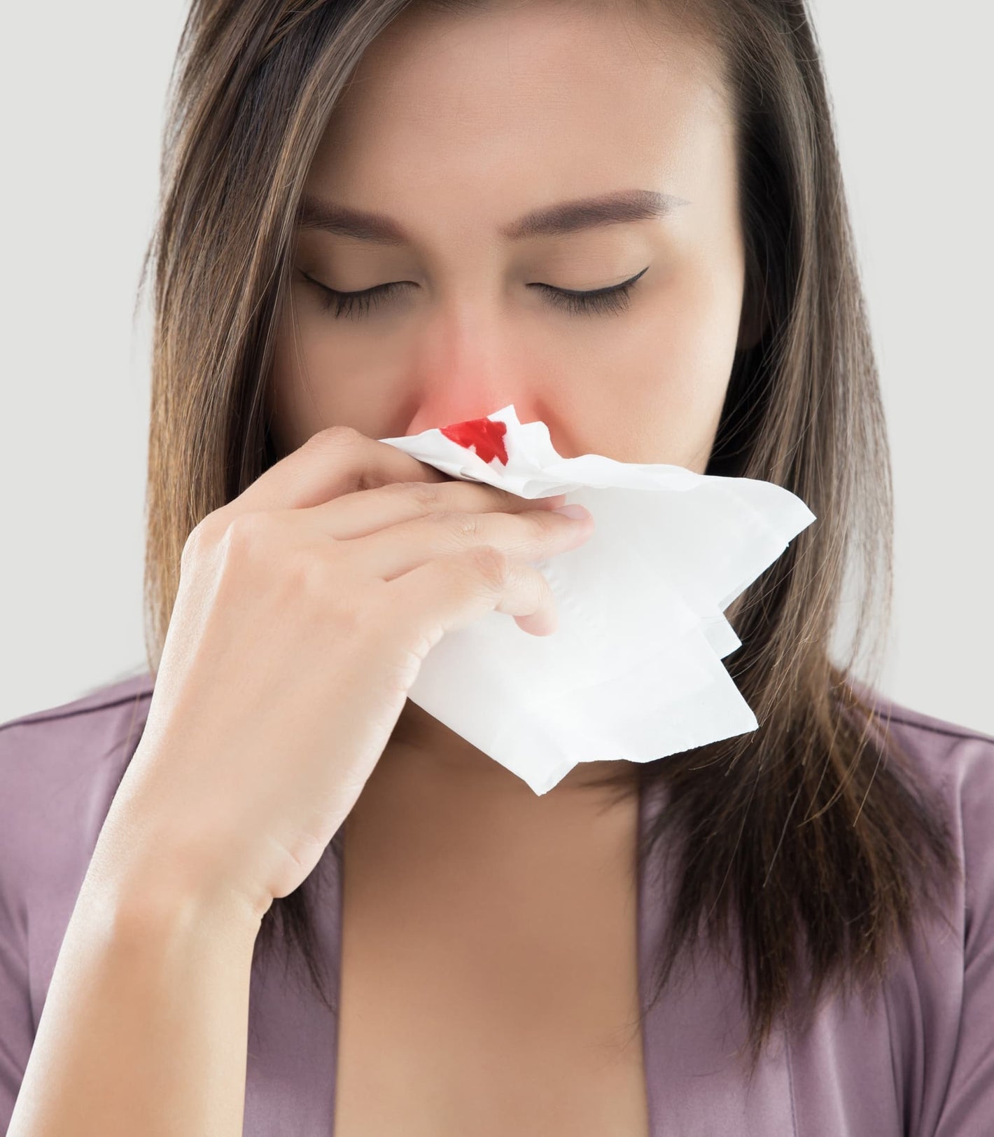 An adult woman managing a common nosebleed, a perfect use case for NozeCalm plugs.