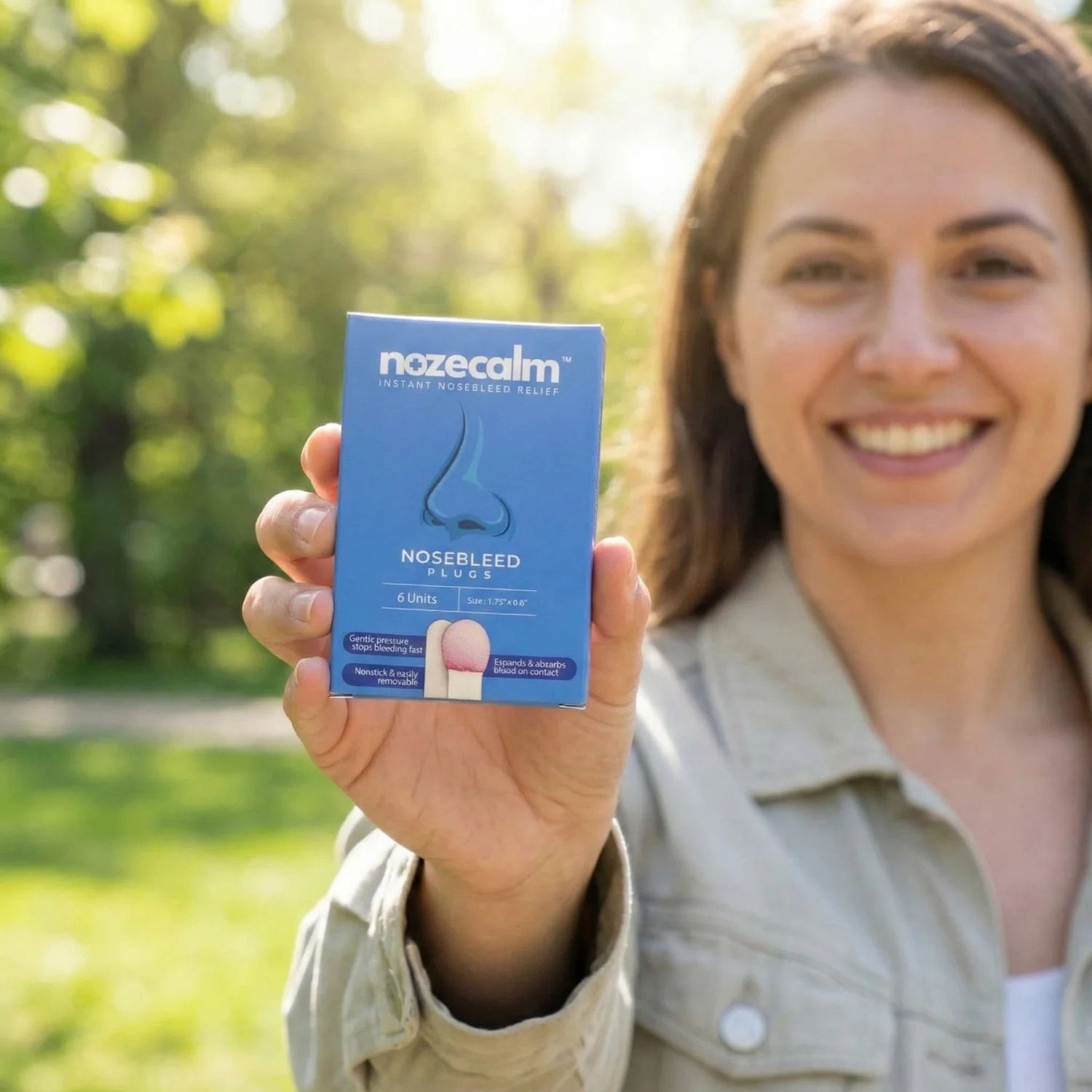 Woman holding a nozecalm nosebleed relief product in a park setting for spring allergies related nosebleeds